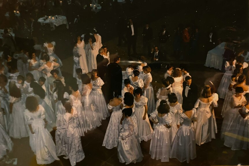 An overview of a group of young women and men in formal wear on a dance floor.