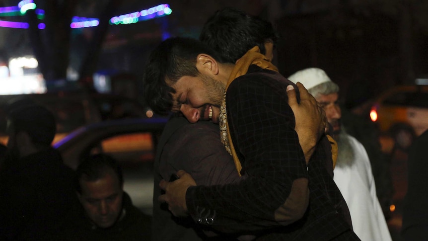 A man cries and embraces another man after a suicide bombing in Afghanistan