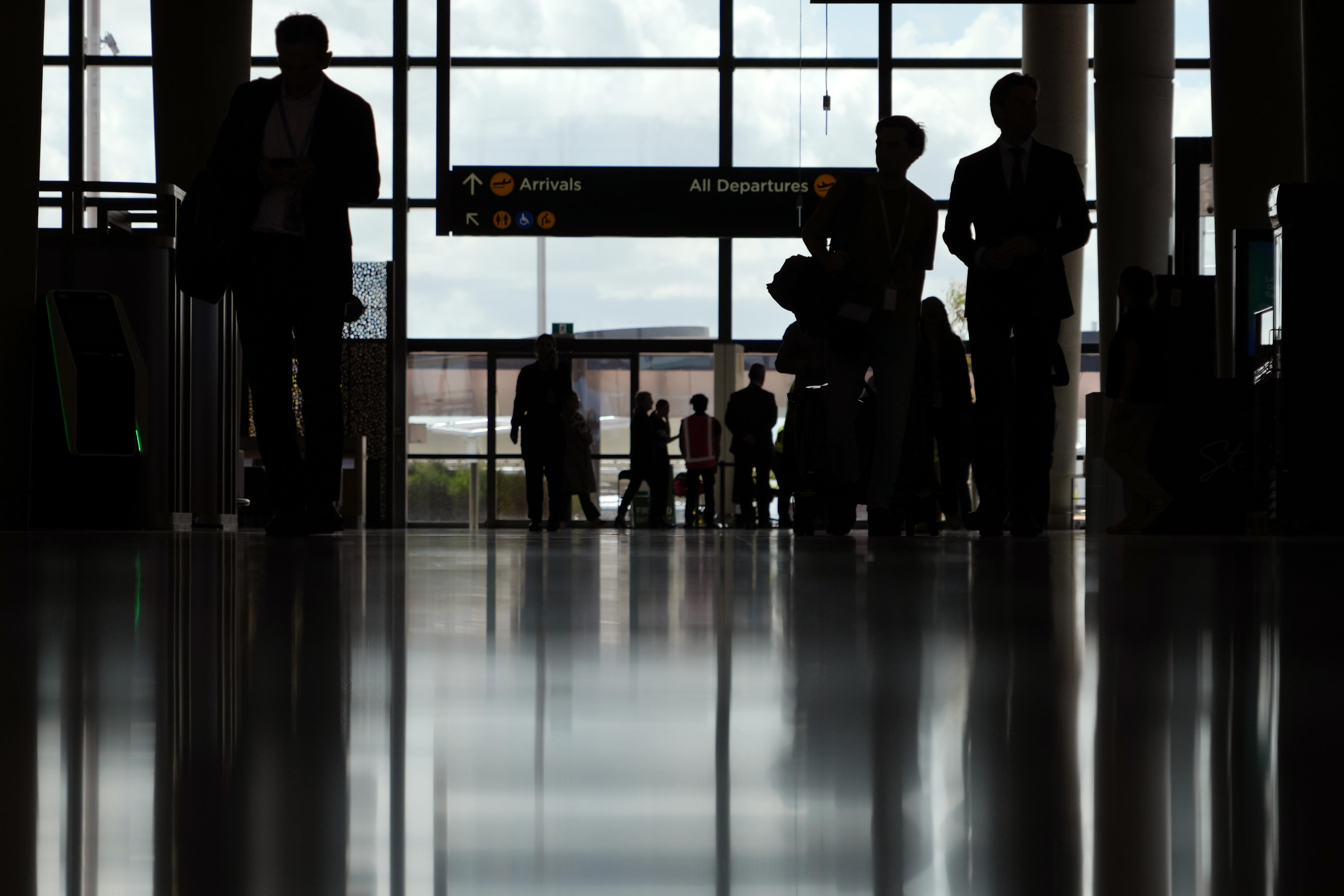 A dark silhouette of passengers inside an airport terminal.