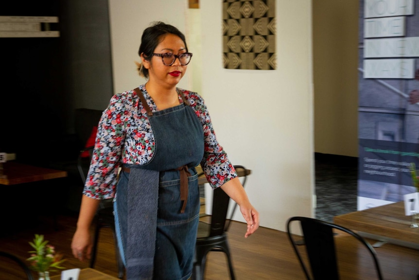 a woman stands behind a counter in a cafe.