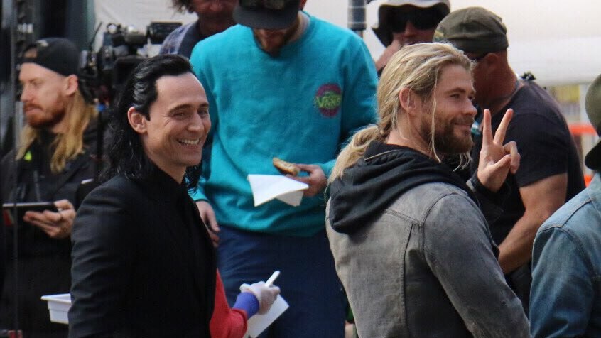 Tom Hiddleston and Chris Hemsworth smile at onlookers on filem set in Brisbane's CBD.