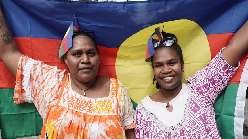 Htadalo Vakie and Emma Koitche hold up  the cultural flag of the Kanak community.