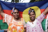 Htadalo Vakie and Emma Koitche hold up  the cultural flag of the Kanak community.