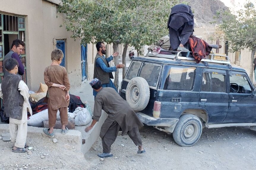 Families pack belonging onto the top of a station wagon.
