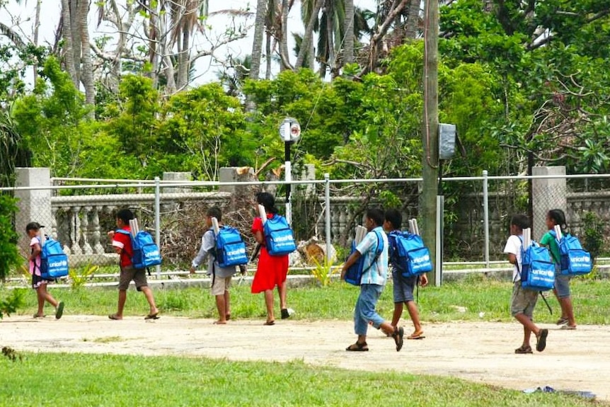 Children wearing backpacks walking to school.