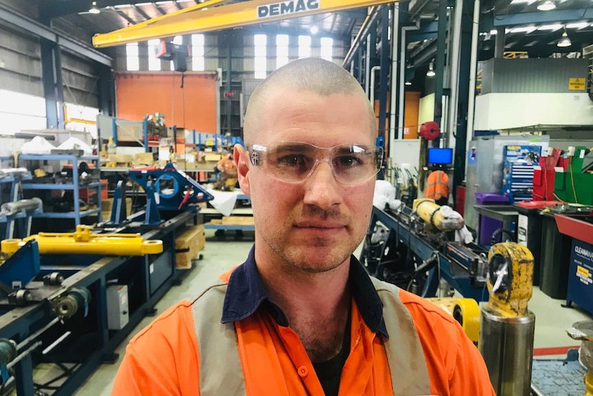 Mining worker Daniel Goscombe wears goggles and high-visibility clothing.