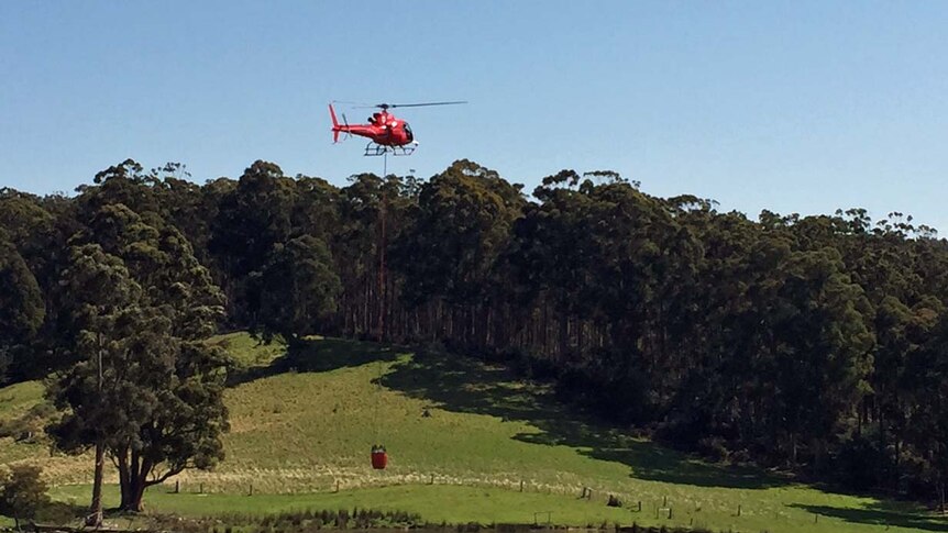 Water-bombing helicopter collects water at a dam near Geeveston.