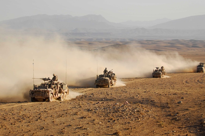 Vehicles drive in convoy across one of Afghanistan's desert.