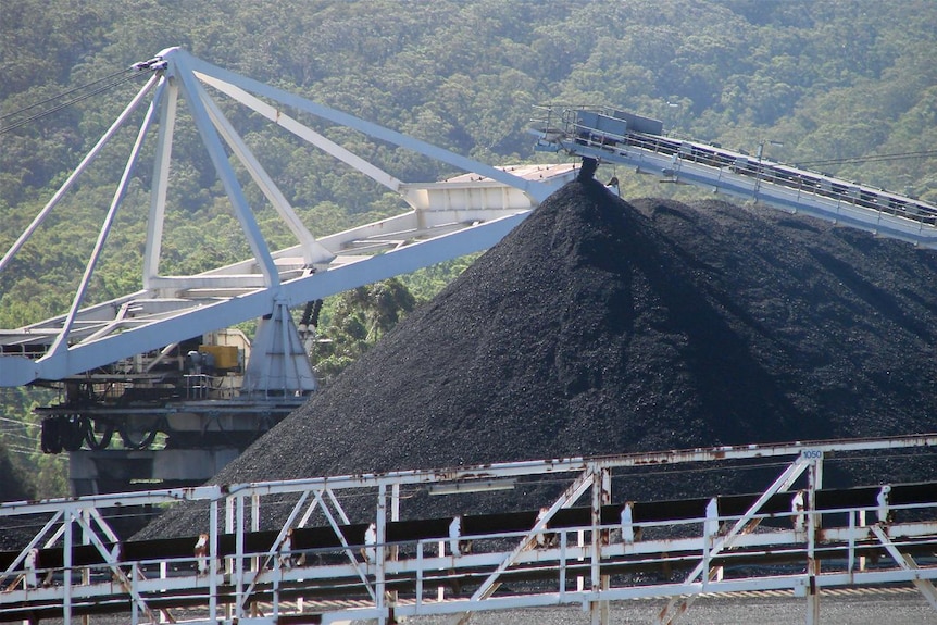 A huge pile of coal sitting amongst mining equipment.