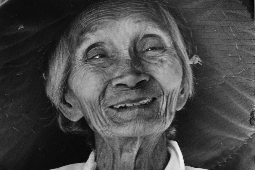 Elderly Chinese lady wearing a wide-brimmed hat smiling at the camera