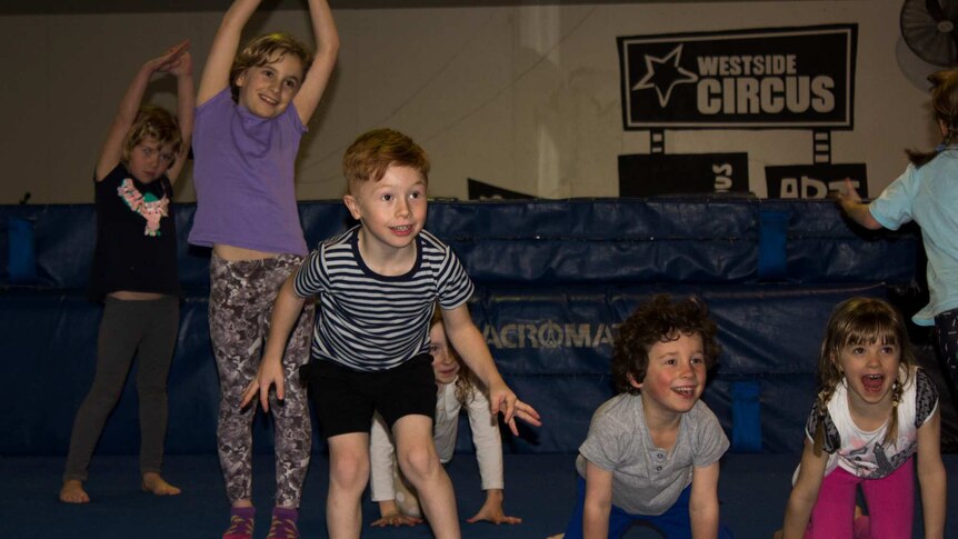 Children in various poses, crash mats and a sign saying 'Westside Circus' in background