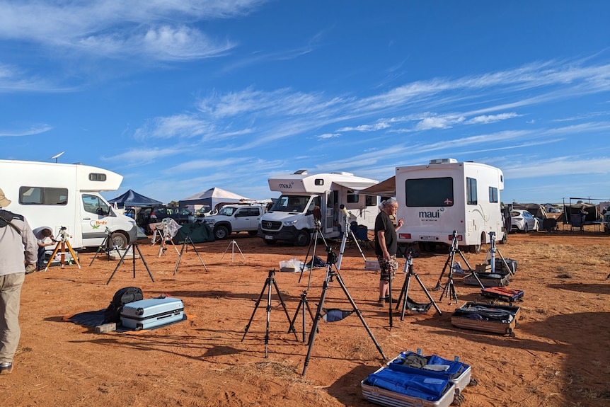 Telescopes, cameras and tripods set up in the middle of a campsite.