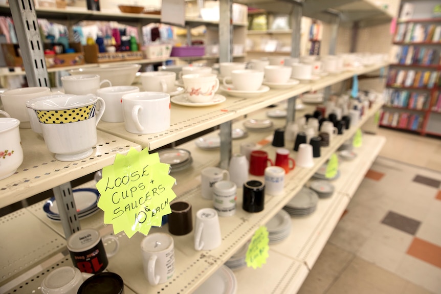 A row of loose cups and saucers in an op shop with a sign marking them at 10 cents each