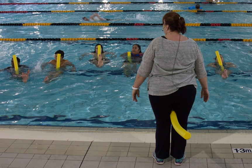 A fitness instructor leads Aboriginal youths in a swimming session