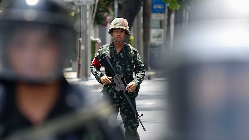 Armed Thai soldier stands behind riot police