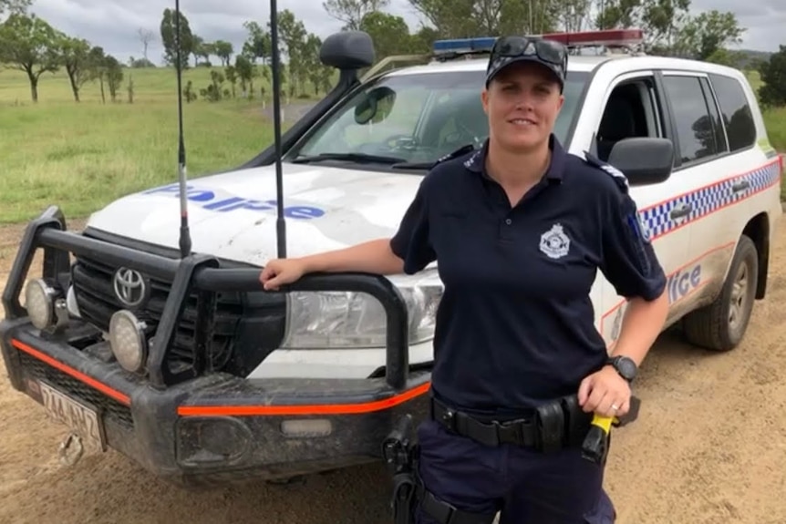 A female police office learning against her patrol car