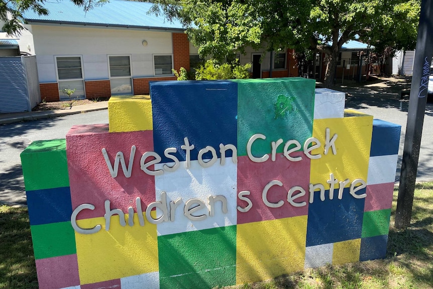 A sign made of colourful blocks reads Weston Creek Children's Centre, with a small building in the background.