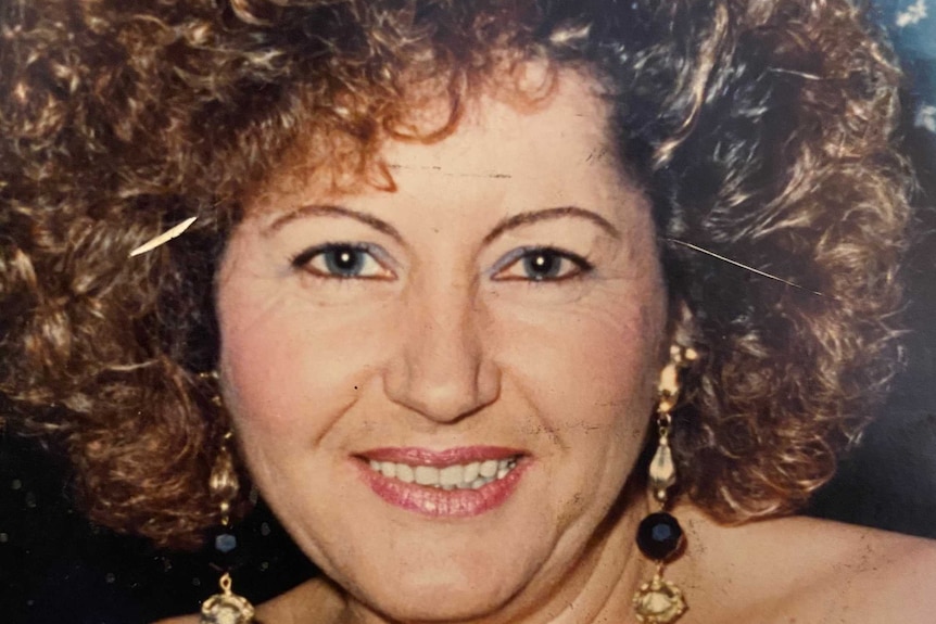 A middle-aged Fotini Atzarakis in gold and black earrings and a cocktail dress.