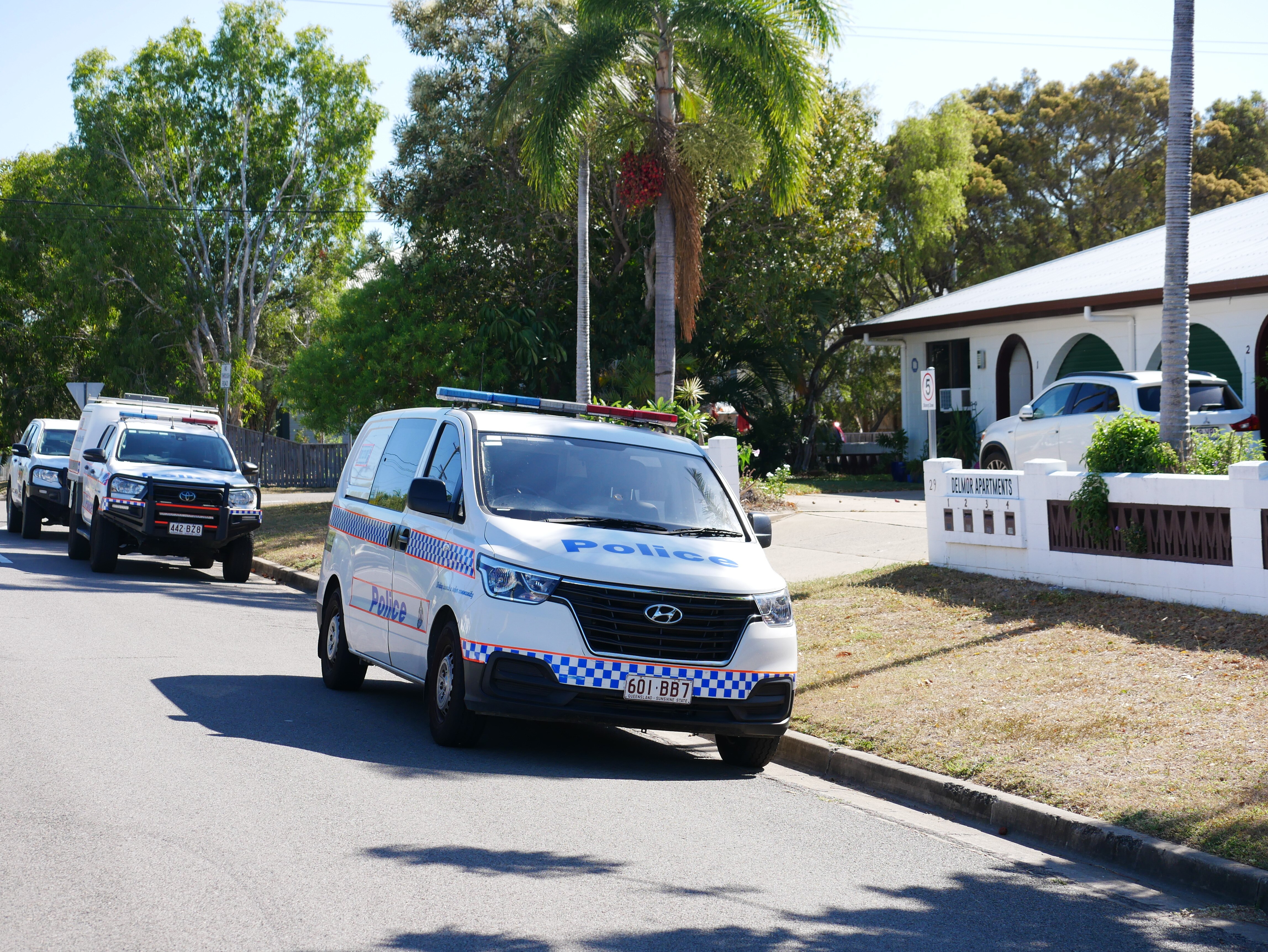 Three white police vehicles lined up outside a Hermit Park home, the house has white arches.