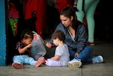 A woman is seen feeding children as they wait to cross the border.