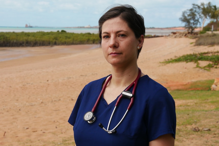 A woman standing on a beach with a stethoscope around her neck.