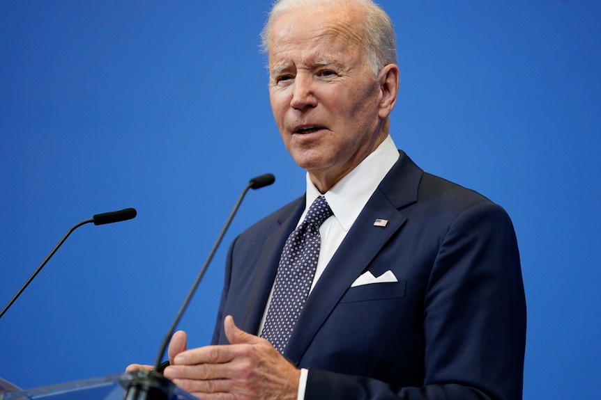 President Joe Biden stands at a lectern addressing world leaders in Brussels