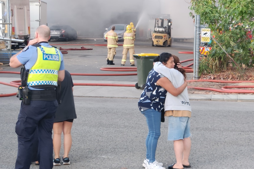 Women embrace at the scene of a fire