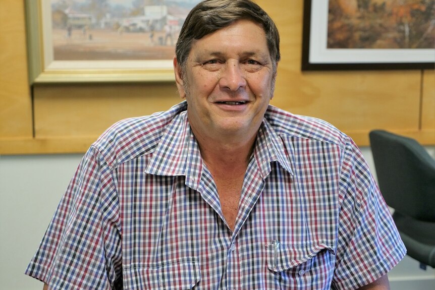 Nev Ferrier, brown hair, light coloured eyes smiles at the camera, checkered white, red, blue, black and grey shirt.
