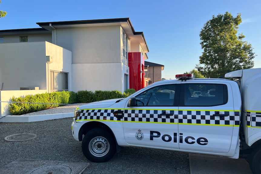 A police car outside a two-storey house. 