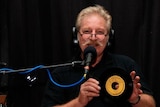 man with radio microphone holding a 45rpm record.