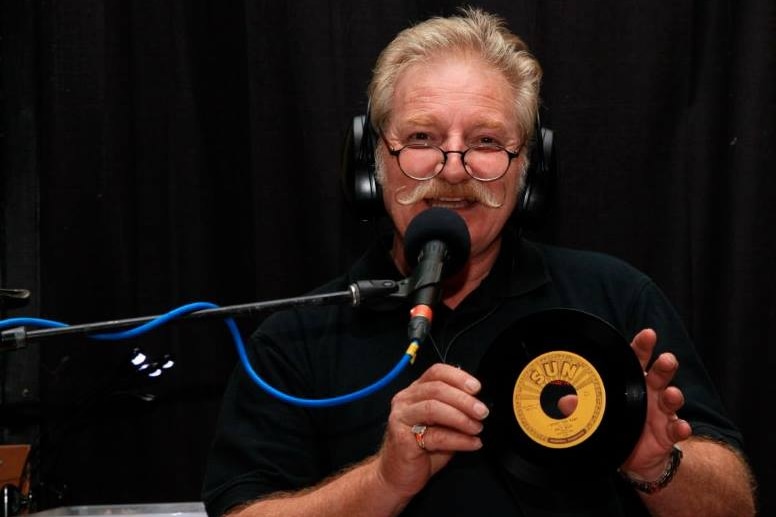 man with radio microphone holding a 45rpm record.