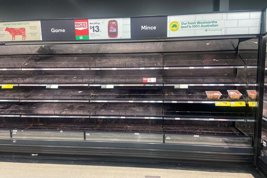 A Woolworths meat section stands empty with only a two packets of meat left for customers. 
