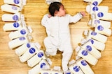 A baby surrounded by bags of breastmilk.