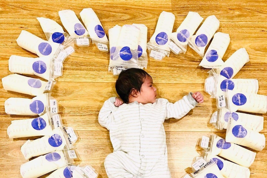 A baby surrounded by bags of breastmilk.