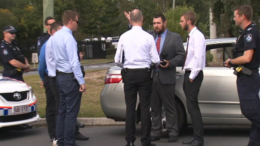 Detectives speaking to a group of men on the side of the road