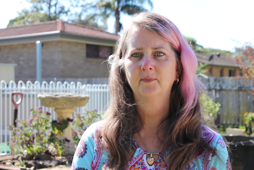 Woman looks into the camera with sombre expression. 