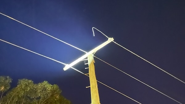 A power pole with three wires, one of which has been cut.