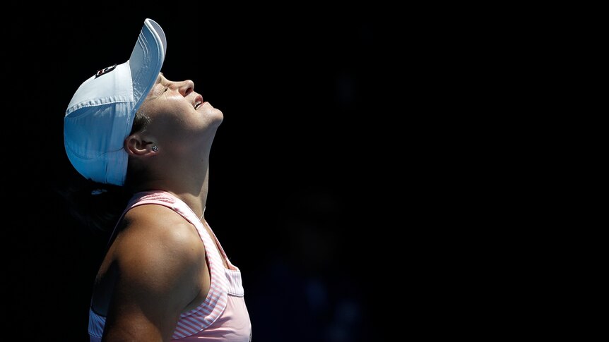 A female tennis player grimaces as she looks towards the sky