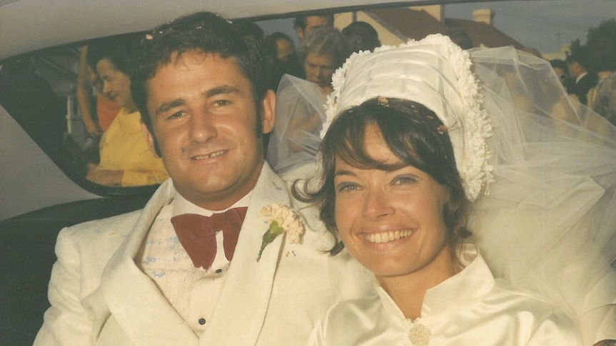 A vintage photograph of a couple in the back of their car on their wedding day