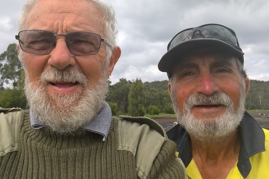 Deux hommes aux cheveux gris et barbus prennent un selfie.