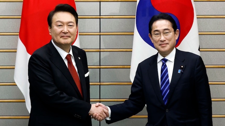South Korean President Yoon Suk-yeol, left, shakes hands with Japanese Prime Minister Fumio Kishida.