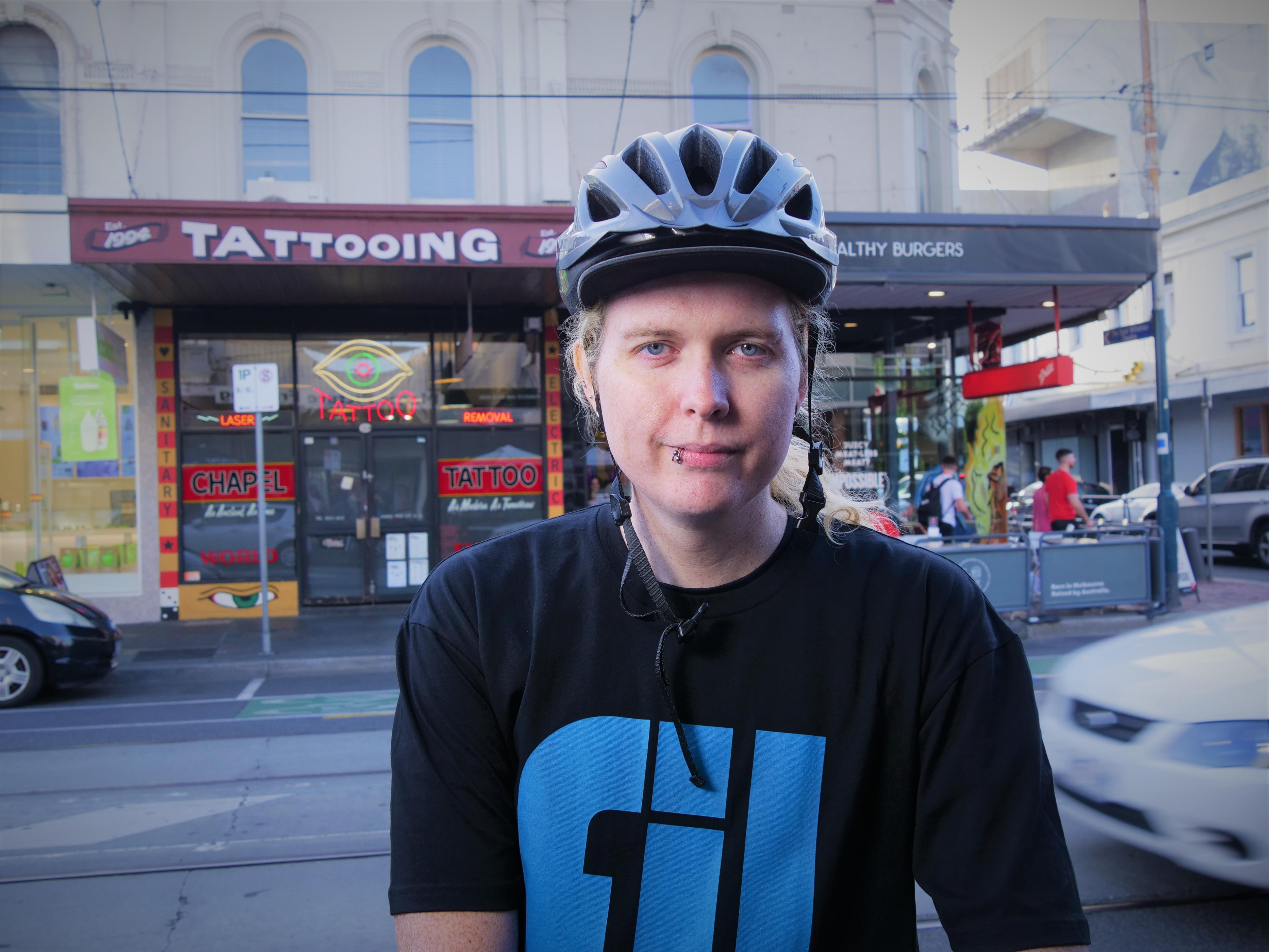 Maxine wearing a helmet looks at the camera while standing on the edge of a road