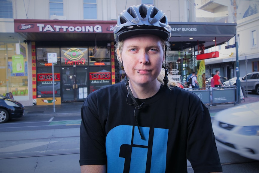 Maxine wearing a helmet looks at the camera while standing on the edge of a road