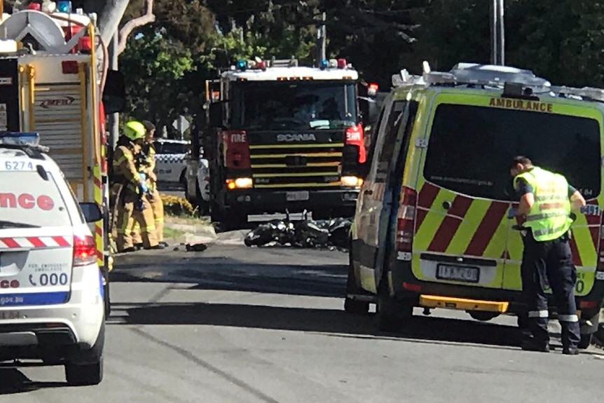 Emergency officials standing around a motorcycle which burst into flames.