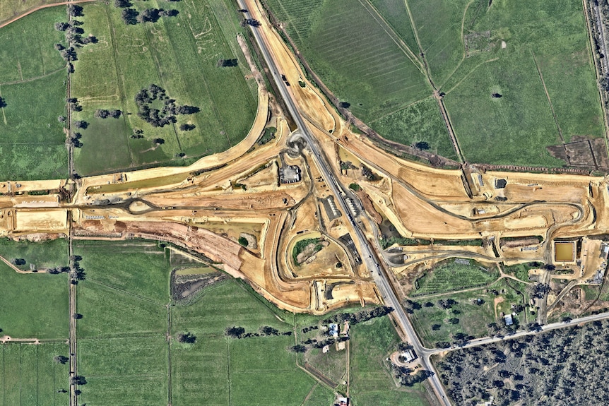 An aerial photo of a construction site amid green farmland