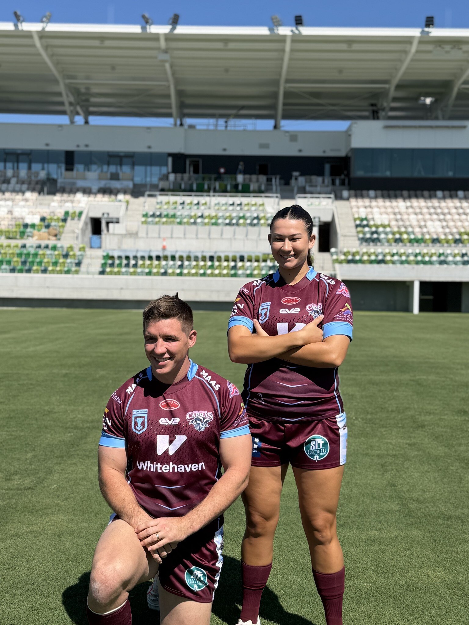 Photo of two footballers - one man and one woman - posing in maroon