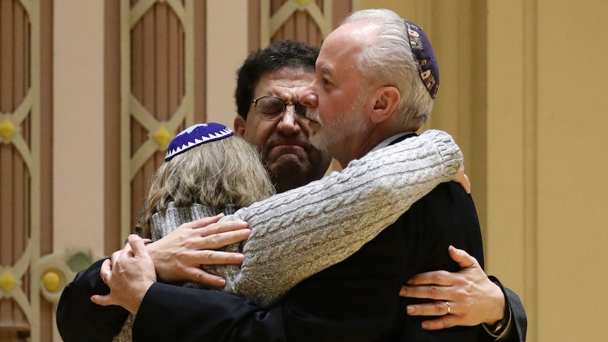 three Jewish people hug in a synagogue