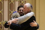 three Jewish people hug in a synagogue