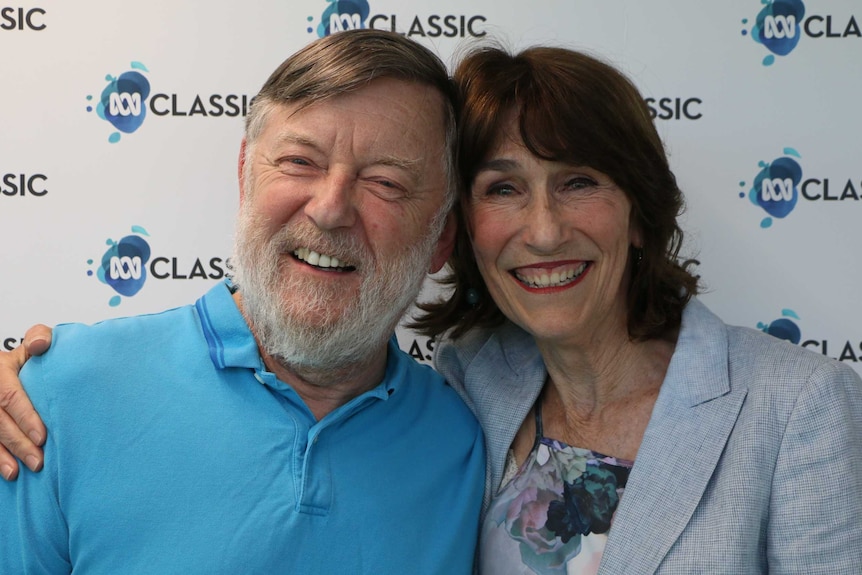 A man with a white beard and a woman with red lipstick smiling