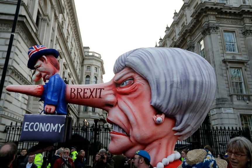 An effigy statue shows a man labelled "Economy"" impaled on the long nose of an angry woman.